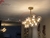 Lustre pendente dourado fosco Grape com globos de vidro, instalado em uma sala de jantar elegante. Lustres Gênesis loja online de Lustres e Iluminação Decorativa