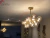 Lustre pendente dourado fosco Grape com globos de vidro, instalado em uma sala de jantar elegante. Lustres Gênesis loja online de Lustres e Iluminação Decorativa