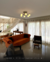 Plafon Moderno Espiral Jabuticaba com 6 globos iluminando uma sala de estar elegante com sofá laranja e cadeiras confortáveis. Lustres Gêneis loja online de Lustres e Iluminação Decorativa