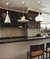 Luminárias de teto pendentes modernas de alumínio em uma cozinha com balcão. Lustres Gênesis loja online de Lustres e Iluminação Decorativa. 