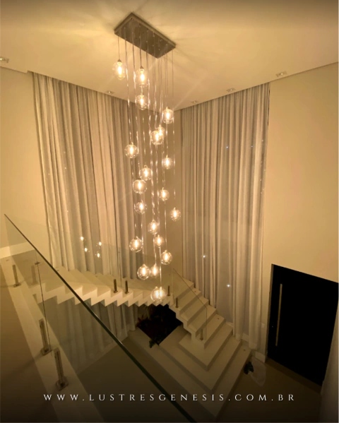 Lustre Pendente Sarvah com 21 globos transparentes em uma escada de pé direito duplo. Lustres Gênesis loja online de Lustres e Iluminação Decorativa