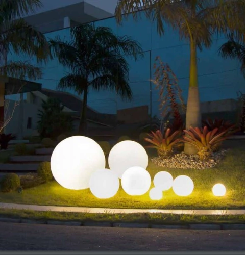 Conjunto de luminárias de chão esfera Soleil branca em um jardim externo à noite Lustres Gênesis loja online de Lustres e Iluminação Decorativa