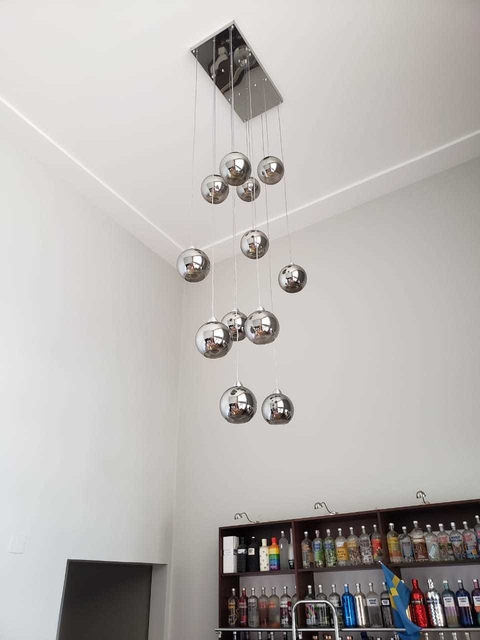 Lustre pendente Sarvah com 12 globos de vidro fumê, base cromada, instalado em ambiente com pé direito duplo.