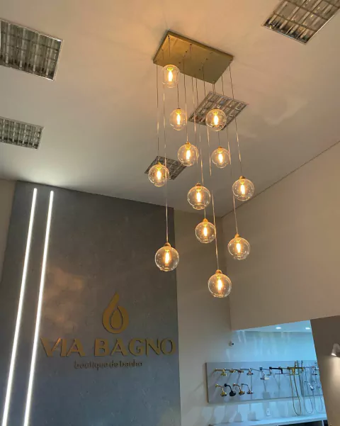 Lustre Pendente Sarvah com 12 globos transparentes em ambiente interno. Lustres Gênesis loja online de Lustres e Iluminação Decorativa