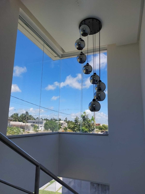 Lustre Pendente Sarvah Moderno com 8 globos fumê espelhados, instalado em uma área com pé direito duplo. Lustres Gênesis Site online venda de Lustres e Iluminação decorativa