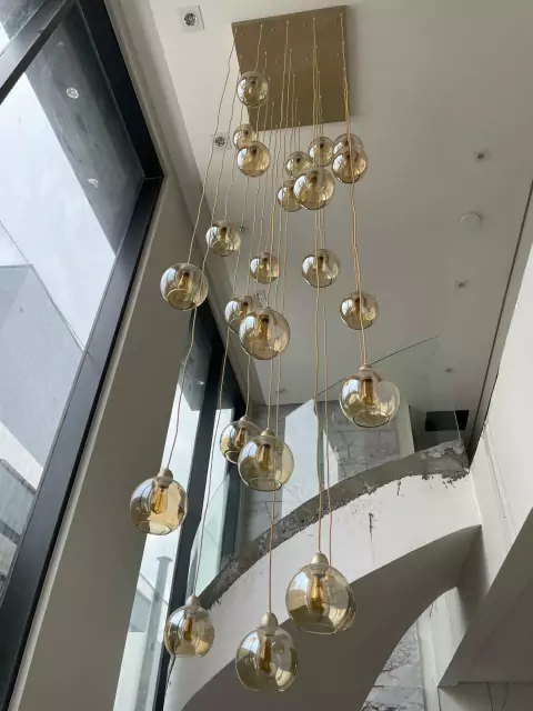 Lustre Pendente Sarvah com 30 globos conhaque espelhados em uma casa de pé direito duplo. Lustres Gênesis Site online venda de Lustres e Iluminação