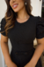 Modelo usando vestido midi preto de malha lese, com mangas bufantes, em ambiente elegante.