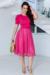 Mulher usando um vestido midi pink com saia de tule forrada, segurando uma bolsa dourada.