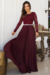 Vestido longo plissado em crepe com renda nas mangas, na cor marsala, com cinto e acessórios elegantes.