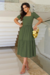 vestido longuete malha lese verde Militar com cinto forrado, posando em ambiente elegante.