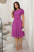 Modelo vestindo um vestido midi de malha lese na cor Fúcsia, posando em uma escada decorativa.