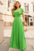 Modelo vestindo um conjunto de blusa e saia longa plissada na cor verde lima, com detalhes em malha lurex.