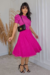 Mulher usando um vestido midi pink com saia em tule forrada, posando em um ambiente moderno