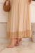 Modelo usando um conjunto de cropped e saia plissada em tom bege, com detalhe em malha floral na barra da saia.