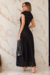 Mulher posando com um elegante conjunto de cropet e saia plissada preto com detalhe em floral na barra, em um ambiente sofisticado.