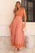 Modelo usando um conjunto de cropet e saia plissada rosa, com detalhes em malha floral na barra da saia.