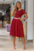 Vestido midi vermelho com detalhe em renda e cintura marcada, usado por uma modelo em ambiente interno.