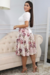 Modelo usando um vestido midi branco floral em piquet com renda, mangas curtas e saia rodada, em um ambiente interno elegante.
