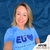 Mulher sorridente usando camiseta azul com a estampa "EU ♥ Alguém com DM". Fundo azul texturizado.