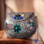 Bolsa Indiana em Metal com design elegante, adornada com pedras coloridas e detalhes em metal. 