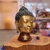 Escultura em bronze da cabeça de Buda, destacando detalhes faciais e cabelo texturizado.