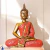 Escultura de Buda Tailandês em tonalidades douradas e vermelhas, sentado em posição de meditação.