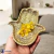 Mão de Hamsa em bronze com flores amarelas em um fundo claro.