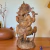 Escultura detalhada de Ganesha em madeira, com acabamento artesanal, mostrando o deus hindu sentado sobre uma flor de lótus, com seus quatro braços e um pequeno rato aos pés.