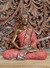 Escultura de Buda Tailandês em posição de meditação, com detalhes em bronze e vermelho, em fundo de madeira entalhada.