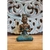 Escultura Balines de bronze de 16 cm, representando uma figura sentada em posição de meditação, com detalhes em azul e bronze.