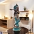 Escultura de Krishna, expressando serenidade e beleza, com detalhes em azul vibrante e acabamento dourado, em um ambiente decorativo.