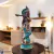 Escultura de Krishna, expressando serenidade e beleza, com detalhes em azul vibrante e acabamento dourado, em um ambiente decorativo.