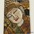 Painel decorativo de Buda em madeira com detalhes dourados e flor de lótus ao fundo.