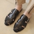 Sandalias de cuero negro con diseño trenzado y hebilla.