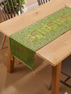 Camino de mesa de seda verde con diseño de elefantes y detalles florales, colocado sobre mesa de madera clara