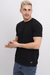 Hombre con remera básica de lycra negra, en pose relajada, mostrando las manos.