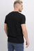Hombre de espaldas vistiendo una remera básica de lycra negra, con pantalones de mezclilla claros.