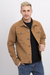 Hombre posando con una chaqueta gabardina color camel, de estilo casual, sobre fondo blanco.