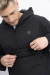 Modelo usando un anorak rompevientos negro con capucha, mostrando un bolsillo oculto con cierre debajo de la solapa.