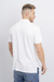 Modelo masculino de espaldas vistiendo una chomba micropique blanca.