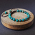 Pulseira de crisocola com contas de pedra natural em tons de azul e verde, sobre uma superfície de madeira.