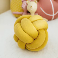 Almofada decorativa Knot Rian Tricot amarela em formato de nó, ideal para quarto de bebê