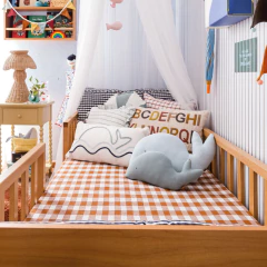 Bicama Woody Tauari com auxiliar e grades palitadas em quarto infantil decorado com móveis de madeira, almofadas e brinquedos.