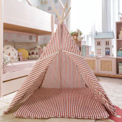 Cabaninha infantil de sarja com listras vermelhas montada em quarto de criança decorado, ao lado de cama e brinquedos.