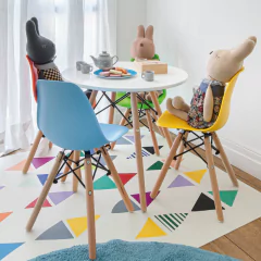 Cadeira Eames Junior amarela com base de madeira natural ao redor de mesa infantil, decorando ambiente lúdico com brinquedos de pelúcia.