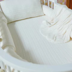 Kit berço Rian Tricot Hanna off-white com 5 peças, incluindo protetor, almofada e manta, decorando berço de bebê.