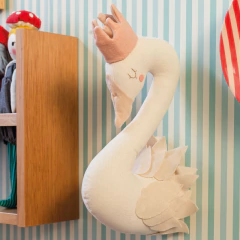 Latifa, cisne de parede nas cores creme e rosa, feito de tecido, pendurado como adorno decorativo em quarto infantil com parede listrada.