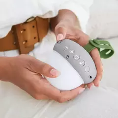 Móbile luminária eletrônica portátil Nozes da Skip*Hop sendo segurado por uma pessoa, destacando o design compacto e os botões de controle.