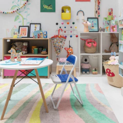 Mesa Eames Junior branca com base de madeira natural em ambiente infantil colorido e decorado, ideal para quartos ou salas de brinquedos.