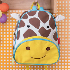 Mochila infantil Skip Hop em formato de girafa, com detalhes amarelos, marrons e azuis, ideal para escola.